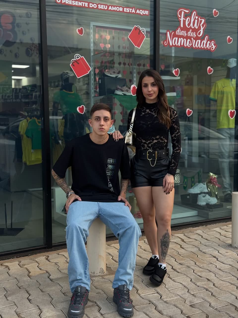 Casal com looks da Traje Style na vitrine da loja